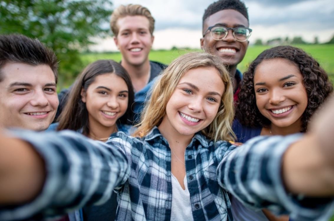 Eine Gruppe junger Menschen macht gemeinsam ein Selfie im Freien